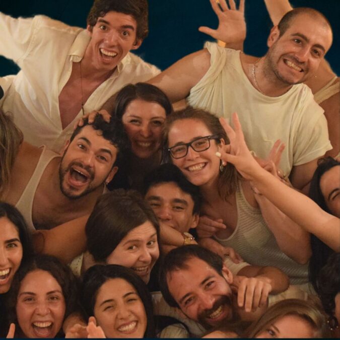 Grupo de personas sonrientes y abrazadas en un ambiente de celebración, vistiendo ropa cómoda y casual, disfrutando de la conexión y la energía compartida en un taller de biodanza