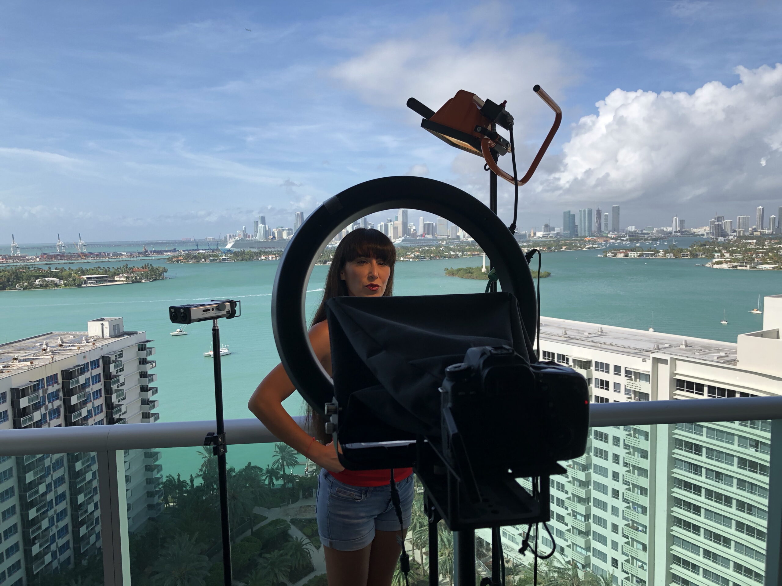 Grace San Martín, presidenta de OPEN-MINDED, en set de producción audiovisual con vista a la bahía de Miami. La asociación abre la monetización de contenidos a sus miembros verificad@s.